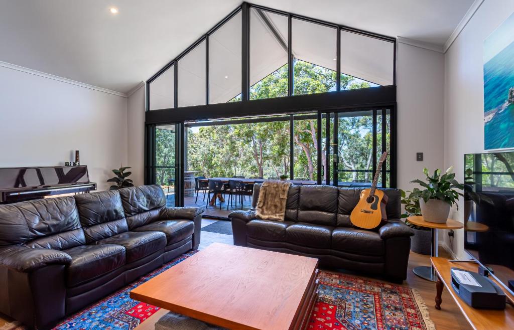 a living room with a leather couch and a guitar at Gum Nuts - New House, family friendly & big groups in Yallingup