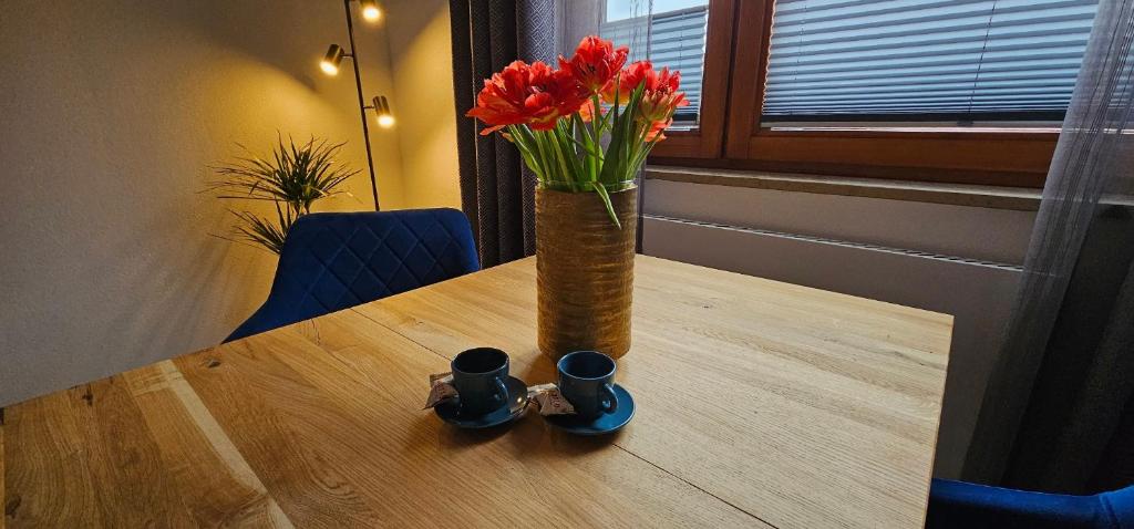un vaso con fiori rossi seduto sopra un tavolo di Elodia Luxus Apartment - WLAN, Magenta TV, Terrasse, Küche, Babybett a Heidenheim an der Brenz