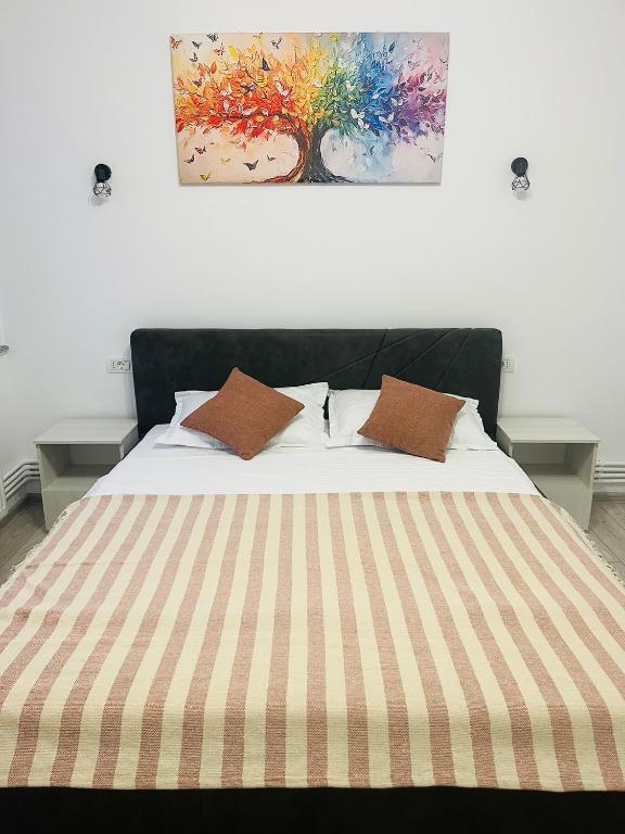 a bed with two pillows and a painting on the wall at DACAFI Luxury Apartment in Hunedoara