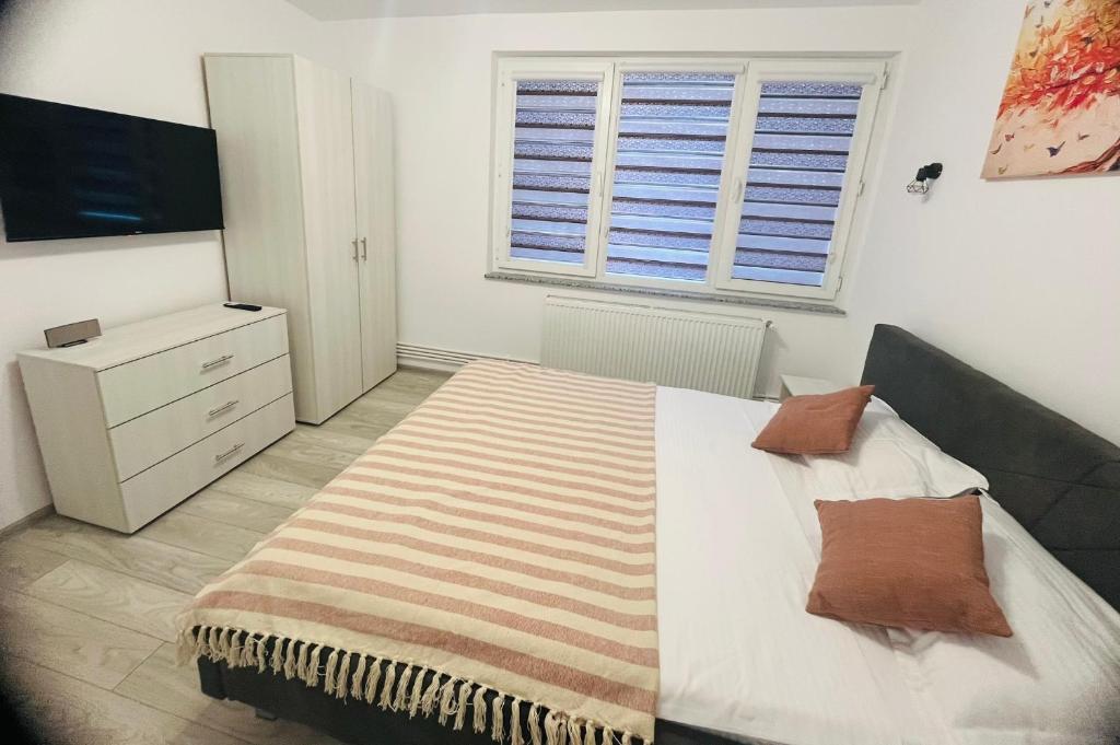 a bedroom with a bed and a dresser and a television at DACAFI Luxury Apartment in Hunedoara