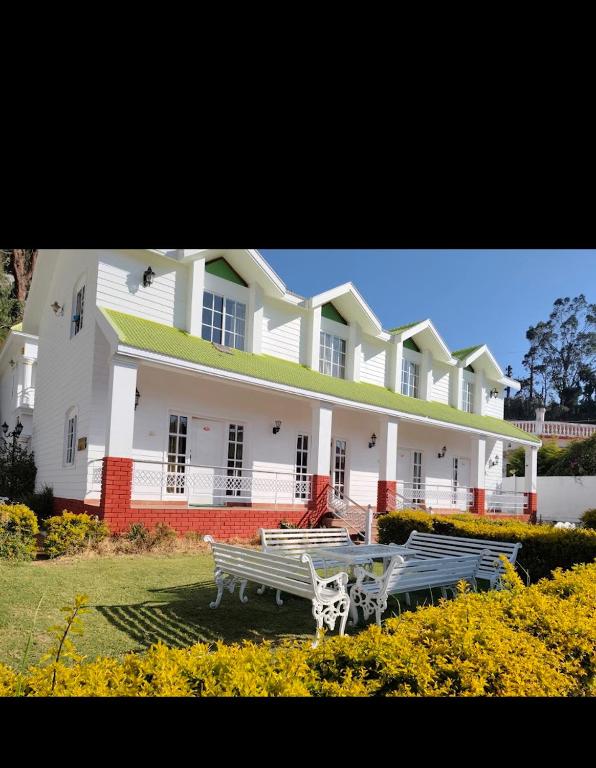 a large white building with benches in front of it at Sunpark in Ooty