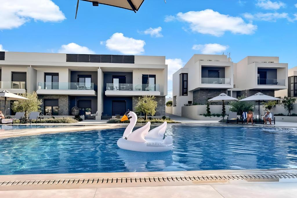 Un cisne inflable en una piscina frente a un edificio. en Olea Valley A24 apartment, en Nikiti