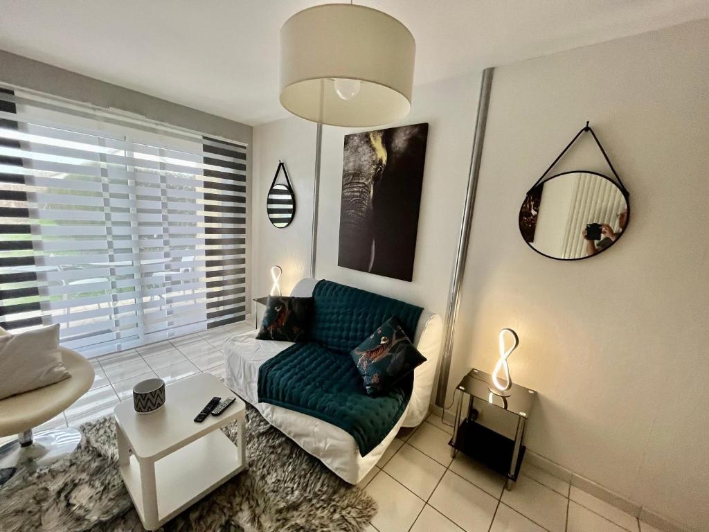 a living room with a green couch and a mirror at Studio ou maisonnette Sarzeau in Sarzeau
