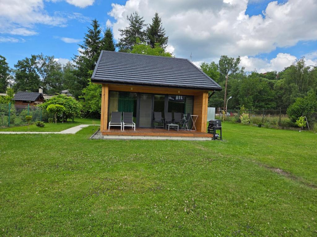 a small cabin with two chairs in a yard at Domek Komfort z jakuzzi przy Parku Zdrojowym in Rabka-Zdrój