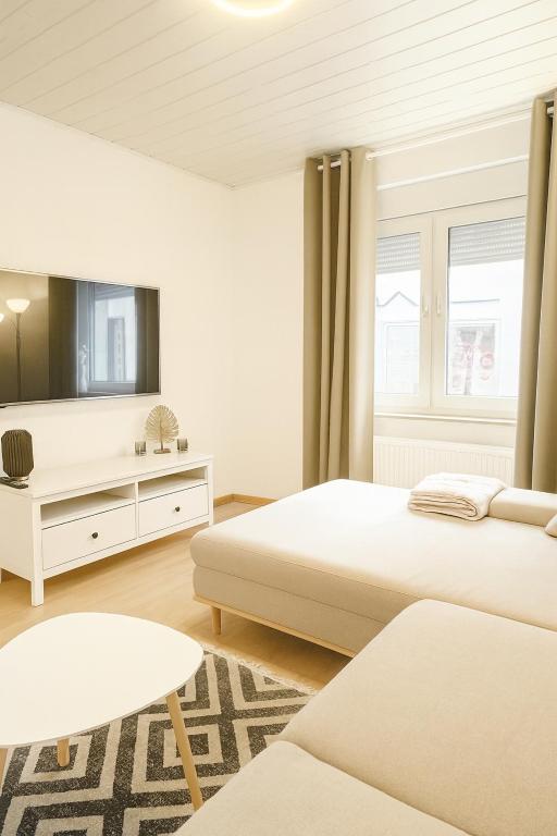 a white bedroom with two beds and a mirror at Dein Ferienhaus in Andernach