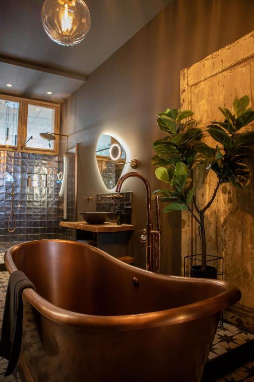 a wooden bath tub in a bathroom with a plant at Het Maashuys in Arcen