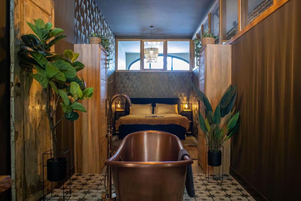 Un baño con bañera de cobre y una cama. en Het Maashuys, en Arcen