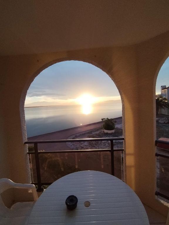 - un balcon avec une table offrant une vue sur le coucher du soleil dans l'établissement Cap sur le Lac, au Barcarès