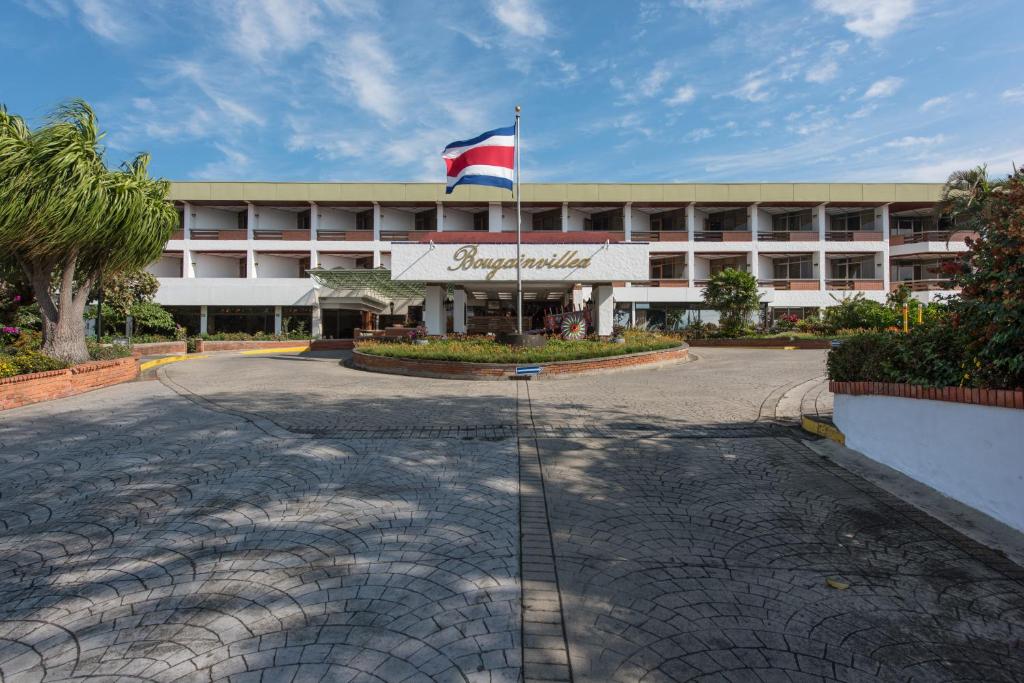 un edificio con una bandera delante de él en Hotel Bougainvillea San José en Santo Domingo