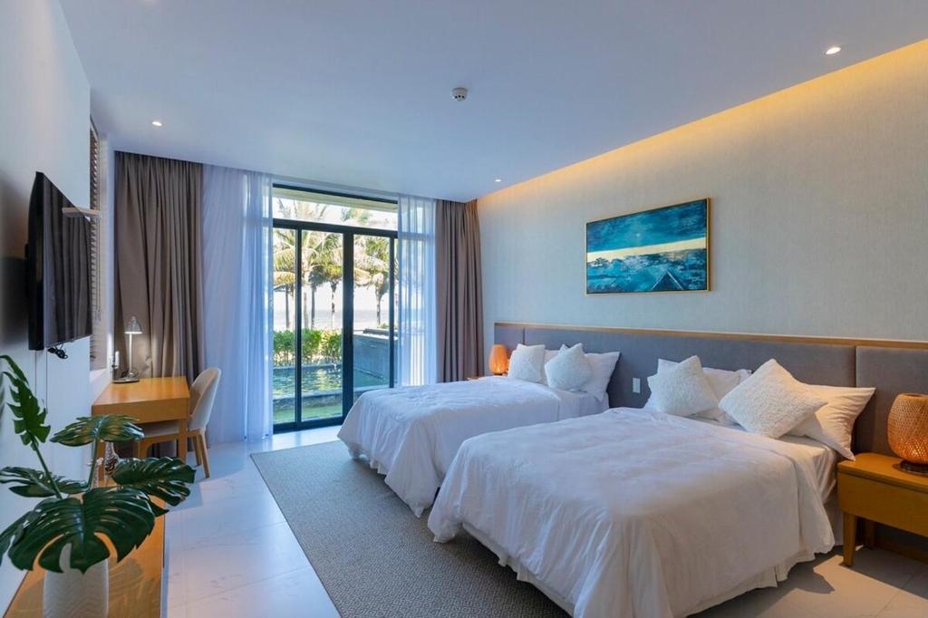 a hotel room with two beds and a window at Wyndham Garden 3Br Villa 5star Resort Beachfront in Cam Lâm