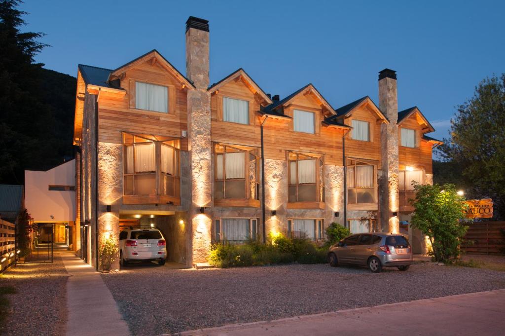 a large building with cars parked in front of it at Del Sauco Apart & Spa in San Martín de los Andes