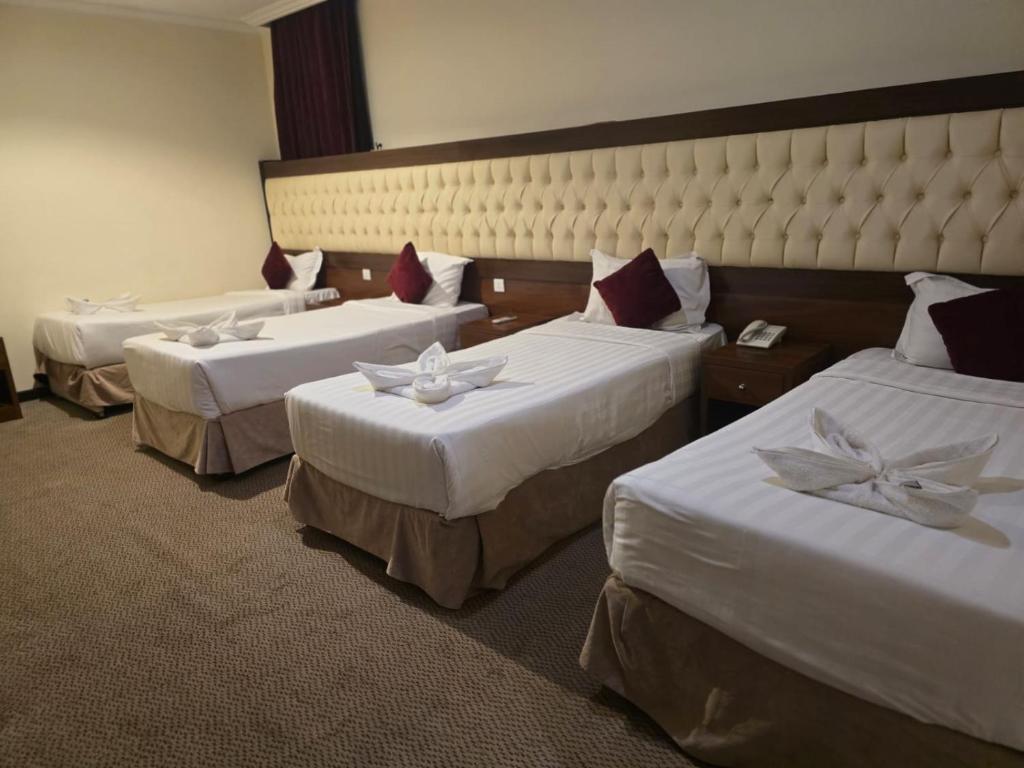 メッカにあるManazel Al Ain Ajyad Hotelのホテルルーム ベッド3台 白いシーツ付