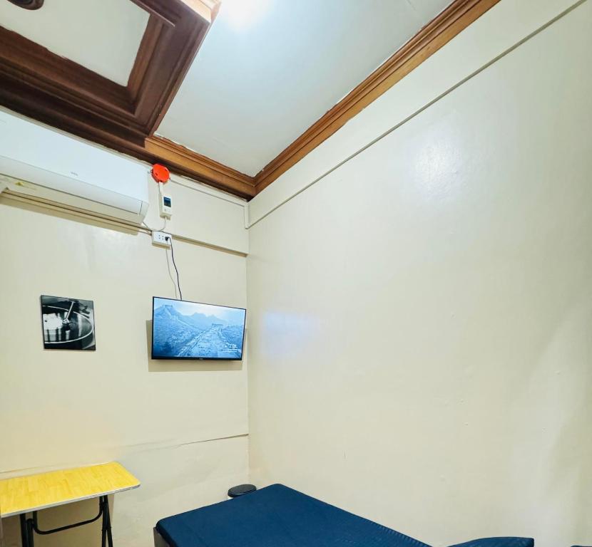 Una habitación con una mesa y un televisor en la pared. en 88Ap Lodging House San Marcelino, en Manila
