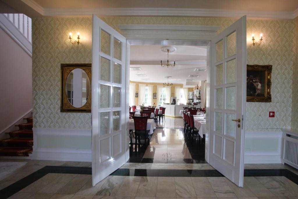 Open white French doors leading into a formal dining room with chandeliers.