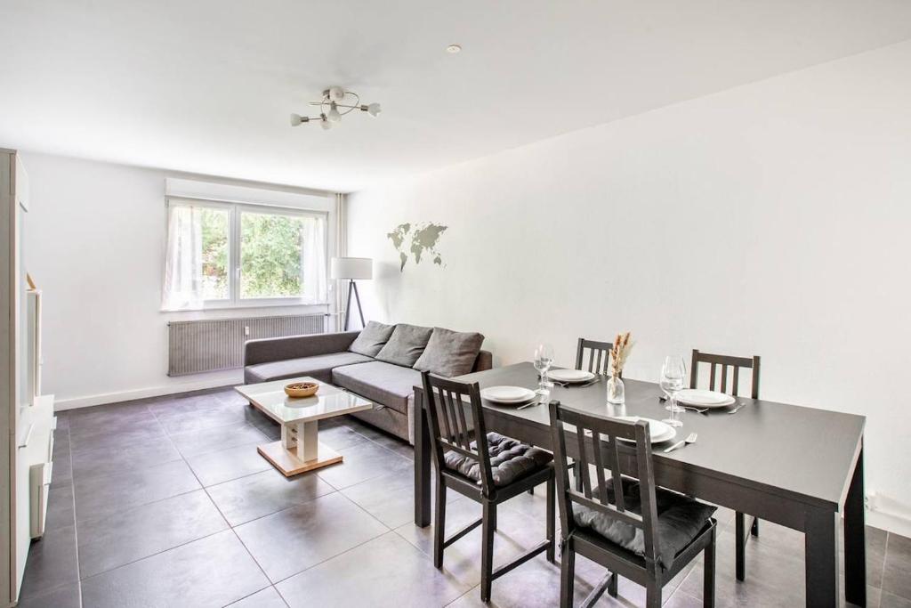 a living room with a table and a couch at Appartement Moderne, À la Passerelle des Trois Pays, HUNINGUE CENTRE in Huningue