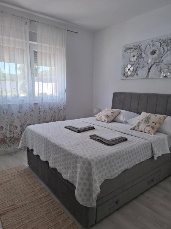 een witte slaapkamer met een bed met twee handdoeken erop bij VILLA ANITA in Sveti Filip i Jakov