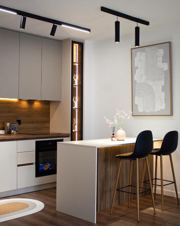 a kitchen with two bar stools and a white counter top at Ohanas Apartment in Prishtinë
