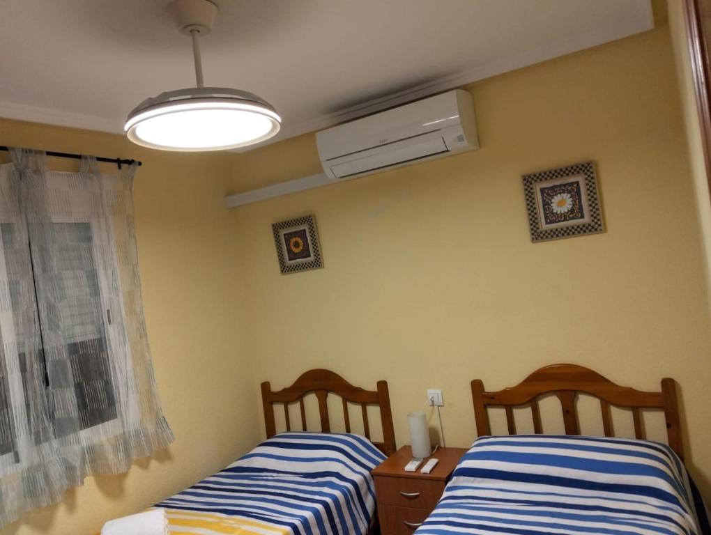1 dormitorio con 2 camas, ventana y ventilador en Yaya Julia, en Santa Pola