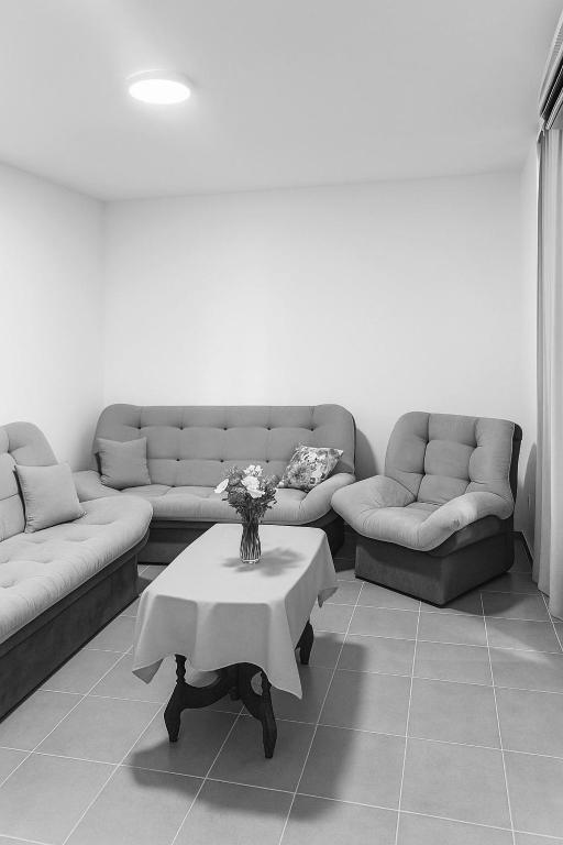 a living room with couches and a table with flowers at Apartman Ulcinj in Ulcinj
