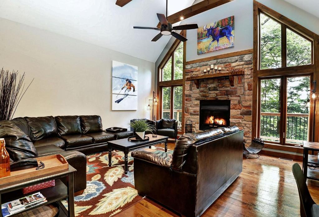 sala de estar con muebles de cuero y chimenea de piedra. en Beautiful 5 Bedroom Chalet for Rent in Stoneham, en Stoneham