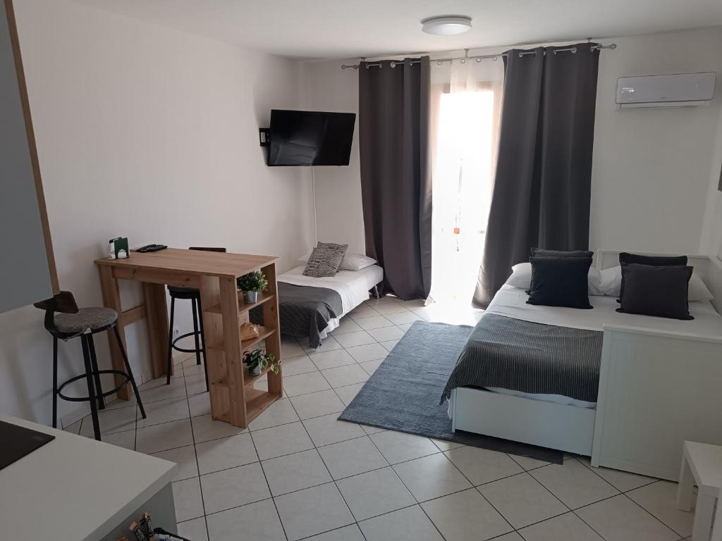 una stanza con due letti, un tavolo e una scrivania di CasaYudi Monolocale con piscina ad Aprilia Marittima