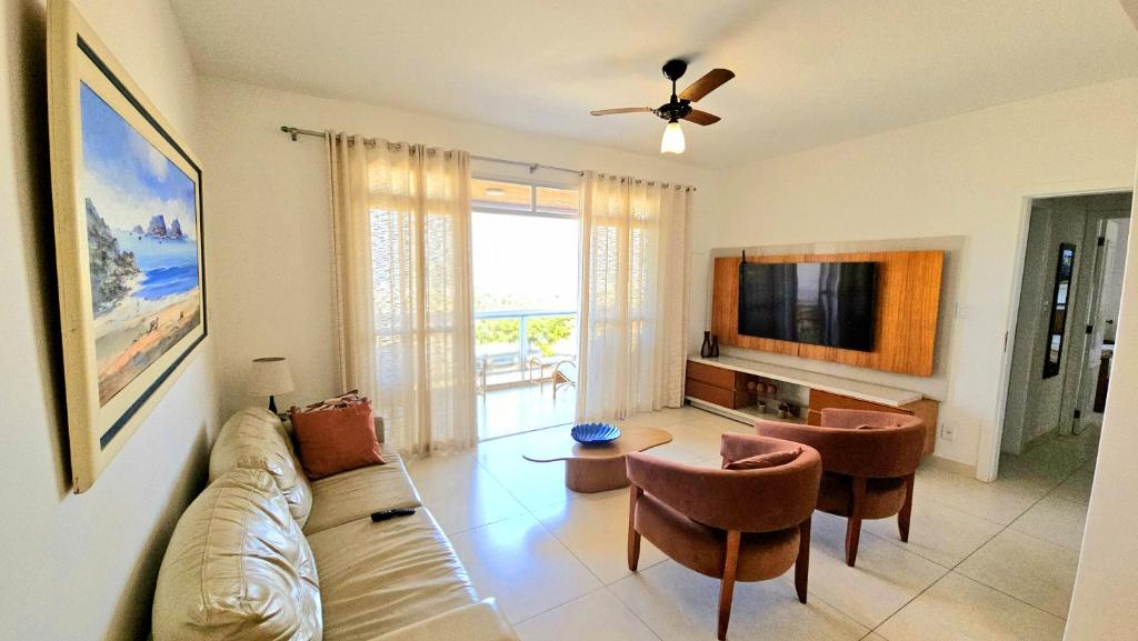a living room with a couch and a tv at Apto Vista Impecável - Praia do Forte in Cabo Frio