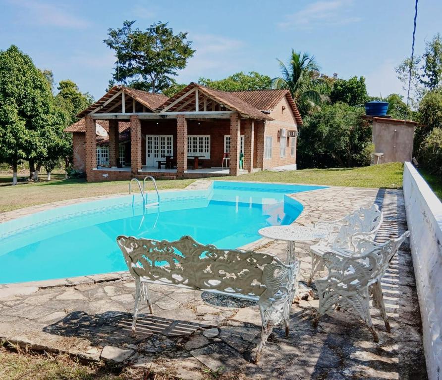 a house with a pool and a table and chairs at Chácara maria bonita in Rio Branco
