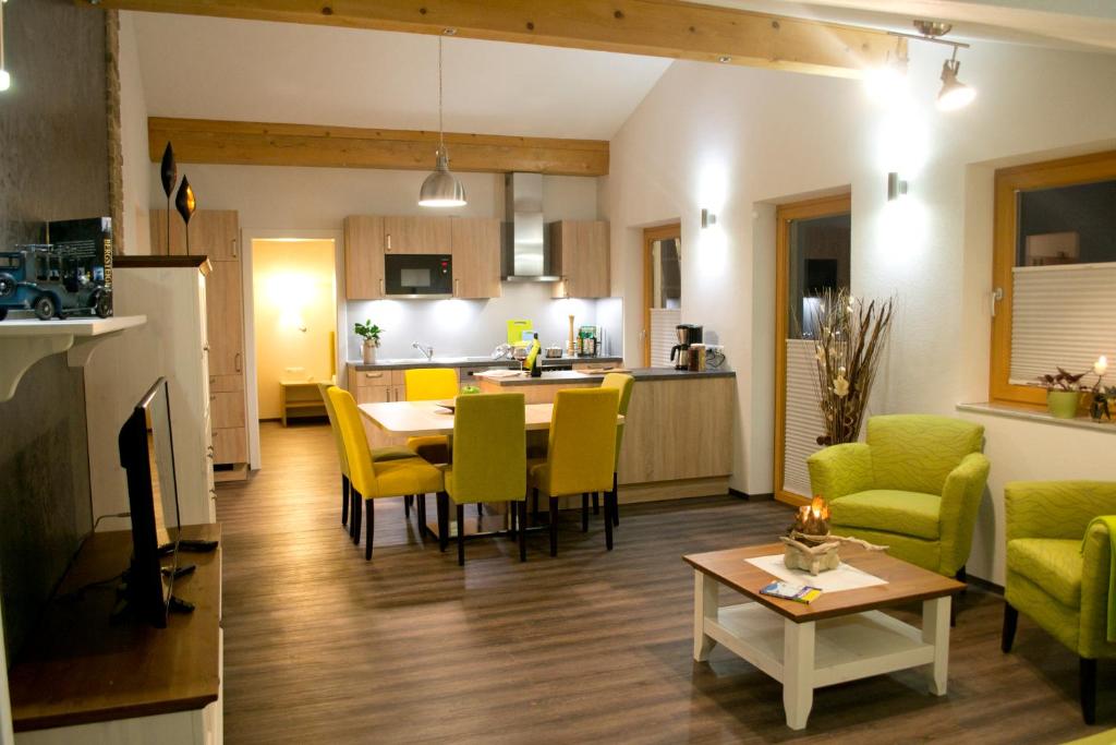 ein Wohnzimmer und eine Küche mit einem Tisch und gelben Stühlen in der Unterkunft Appartement Tirol in Biberwier