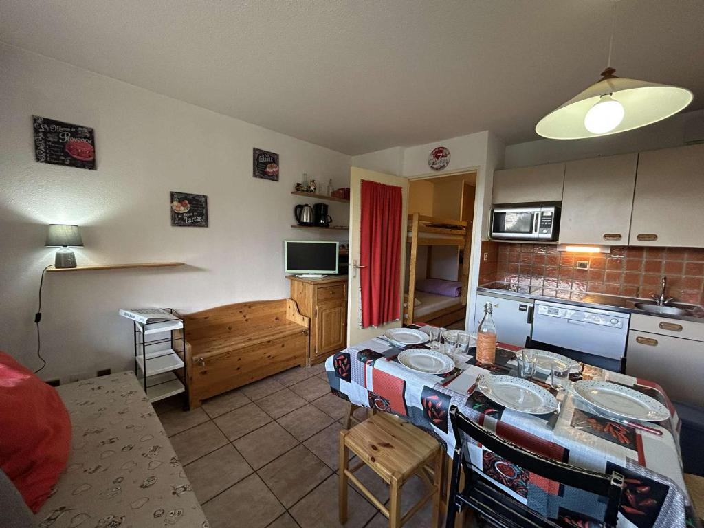 une cuisine avec une table et des chaises dans une pièce dans l'établissement Appartement Montgenèvre 6 pers, skis aux pieds, animaux acceptés, parking - FR-1-330D-70, à Montgenèvre
