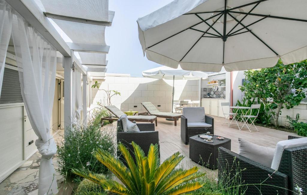 an outdoor patio with chairs and an umbrella at Lovely Home In Punta Braccetto in Punta Braccetto