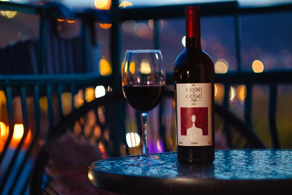 a bottle of wine sitting on a table with a glass at Hotel Tiflis Town in Tbilisi City