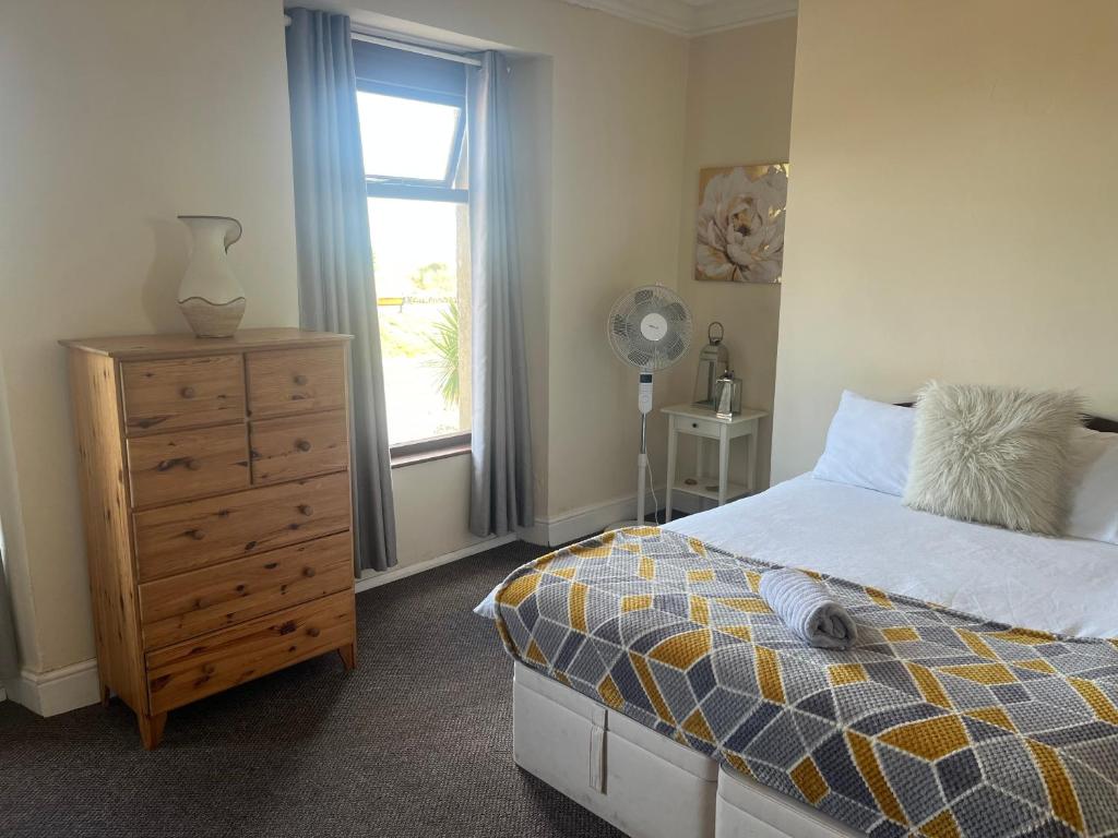 a bedroom with a bed and a dresser and a window at 284 - Room 5 - Beachfront - Fantastic sea views in Swansea