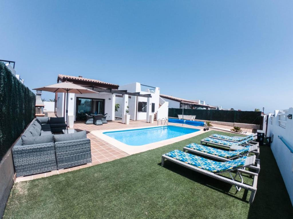 a backyard with a swimming pool and a house at Villa Romans in Caleta De Fuste