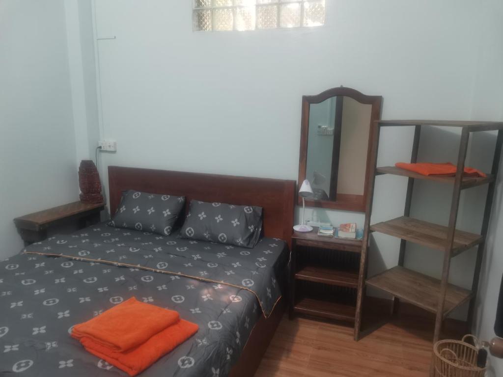 Dormitorio con cama con almohada naranja y espejo en Bar Ang Guesthouse, en Battambang