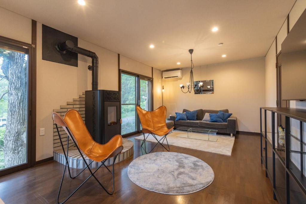 a living room with orange chairs and a couch at Forest and Stars Akakura Luxe in Myoko