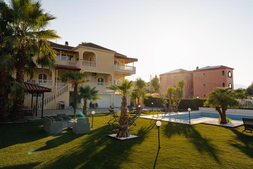 a large building with palm trees in a yard at Villa Ilianna in Igoumenitsa