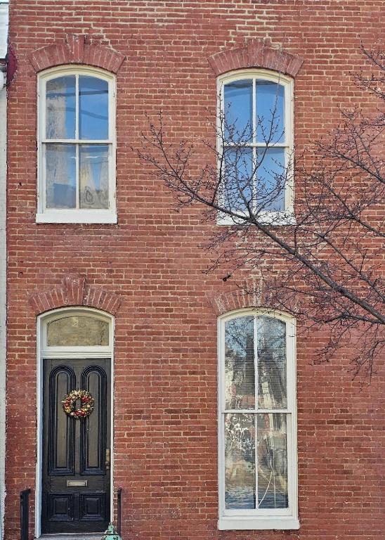 a brick building with a black door and three windows at Baker Park Charm in Frederick