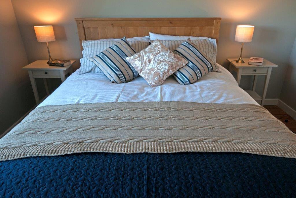 een groot bed met twee lampen op twee tafels bij Willan Cottage in Portrush