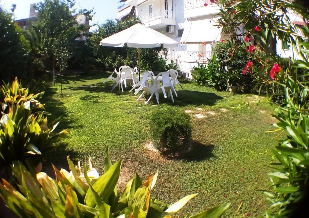 a yard with white chairs and an umbrella at Araliki Apartments & Studios in Loutra Edipsou