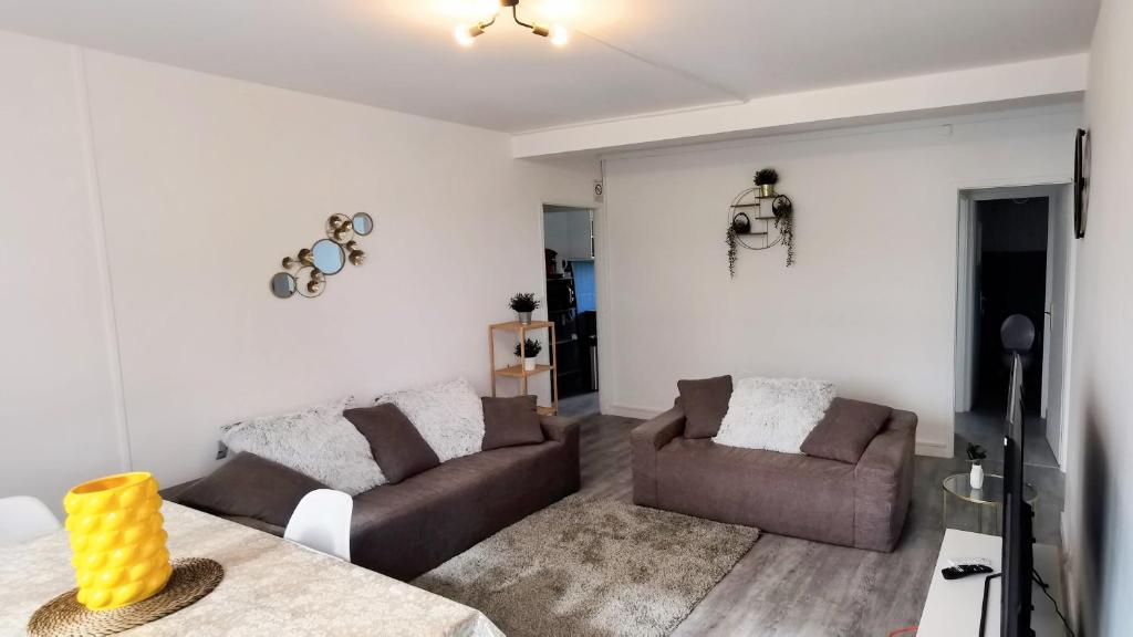 a living room with a couch and a table at Les Erables Appart - 3 chambres - Spacieux et moderne avec balcon, parking et wifi in Saint-Jean-de-la-Ruelle