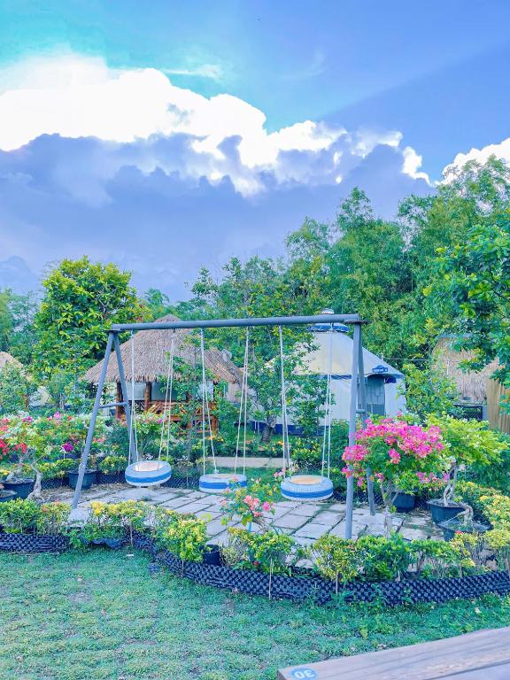 a garden with swings and flowers on a dock at Mekong Camping Deluxe in Ấp Thanh Sơn (1)