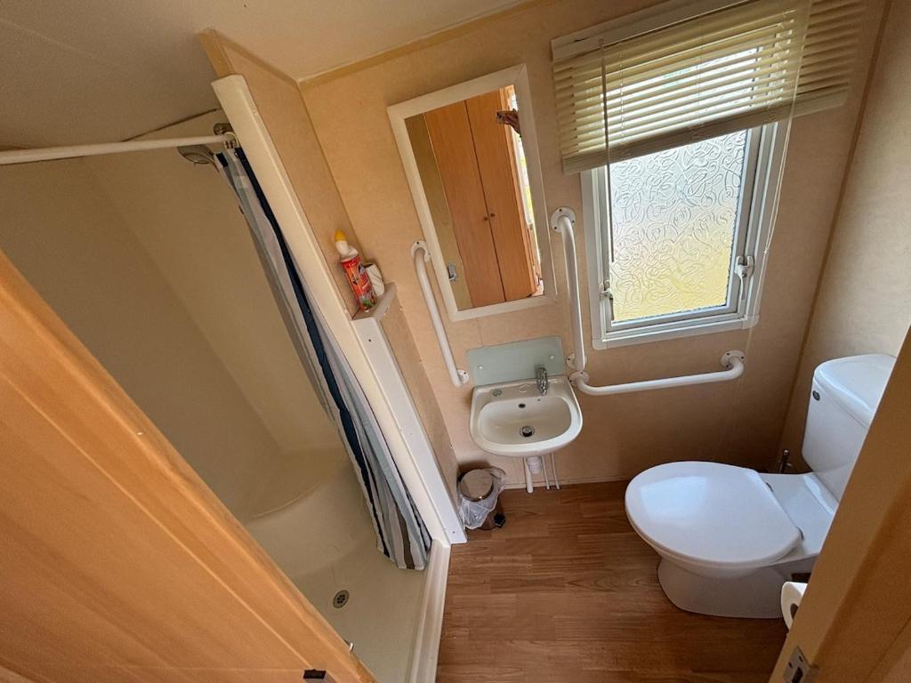 a bathroom with a toilet and a sink and a window at Disabled caravan -ramped decking - Grange Leisure Park, Mablethorpe - Pet friendly and Wifi - Meadow Lakes Caravan & Lodge Hire in Mablethorpe