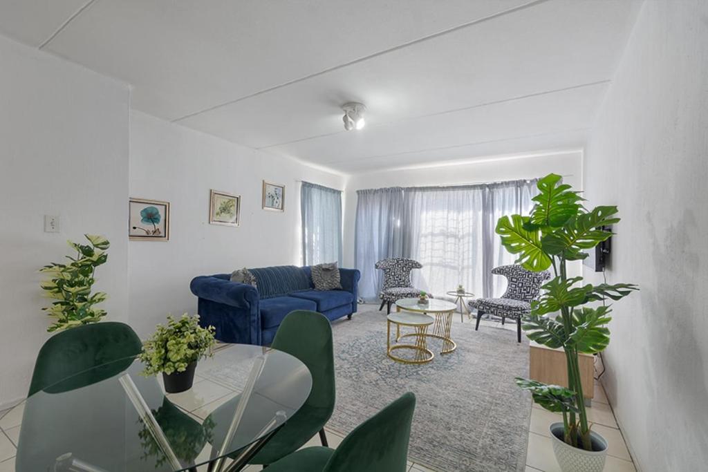 a living room with a blue couch and a glass table at Chic 2BR Apartment in Roodepoort in Roodepoort