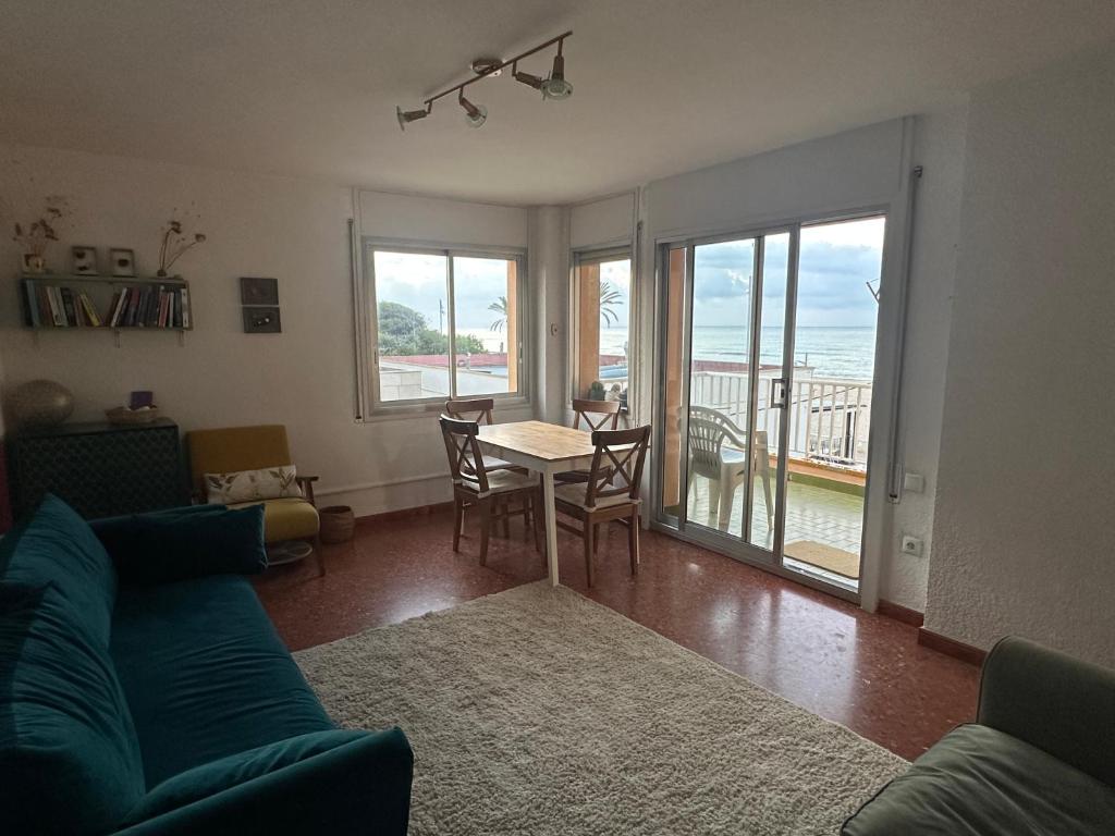ein Wohnzimmer mit einem blauen Sofa und einem Tisch und Stühlen in der Unterkunft Beachfront apartment in Sant Salvador