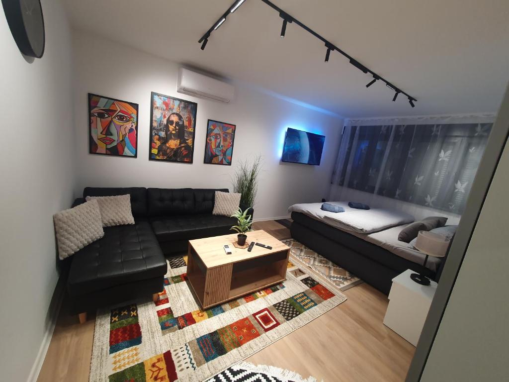 a living room with a black couch and a table at Sofia Apartment free parking in Sarajevo