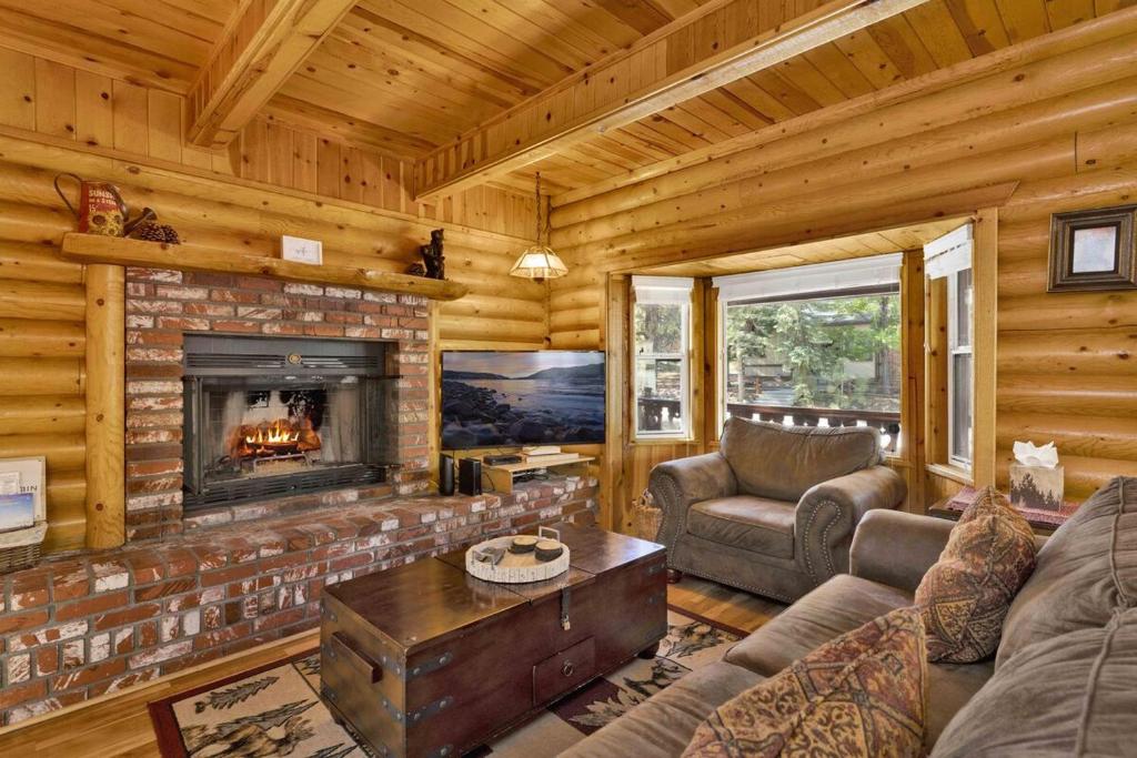 ein Wohnzimmer mit Kamin in einer Blockhütte in der Unterkunft Cub's Cabin / Charming 3-Bedroom Log Cabin Near Big Bear Lake in Big Bear Lake