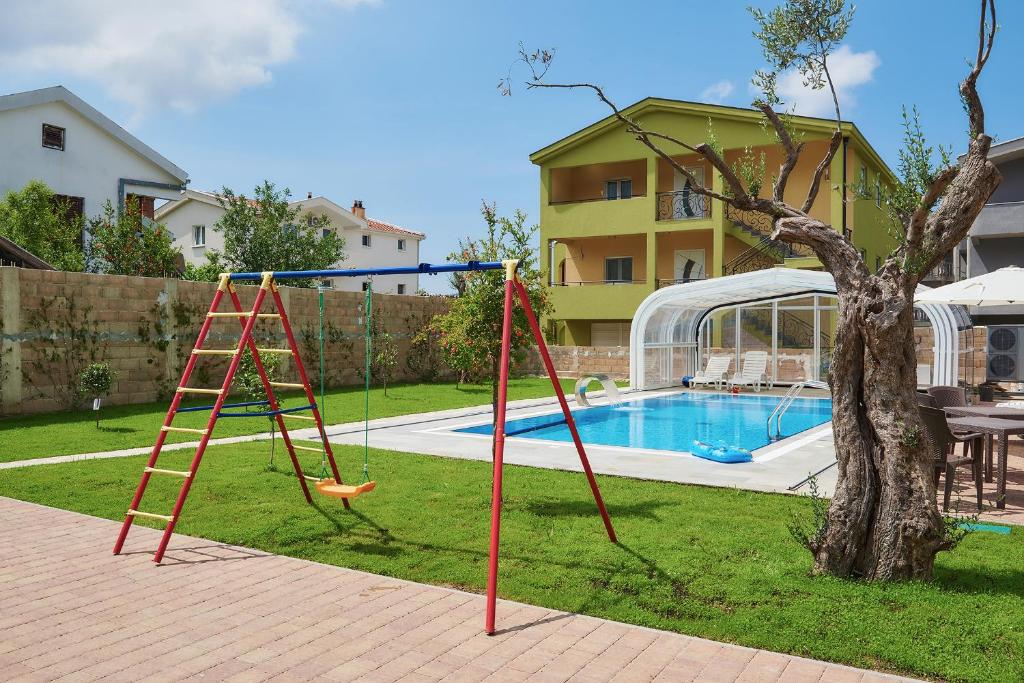 a yard with a swing set and a pool at Apartments Villa FourTuna in Bar