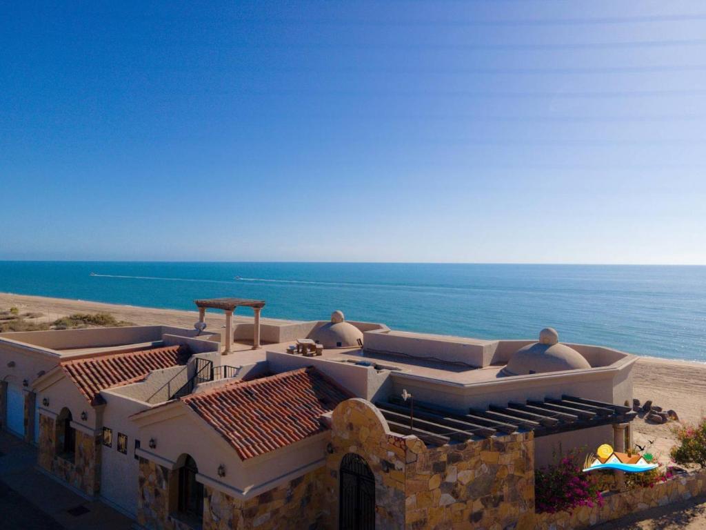 Un edificio con dos hombres sentados en un balcón mirando el océano. en Casa Serenity - Beachfront Vacation Rental in San Felipe, en Don Pancho