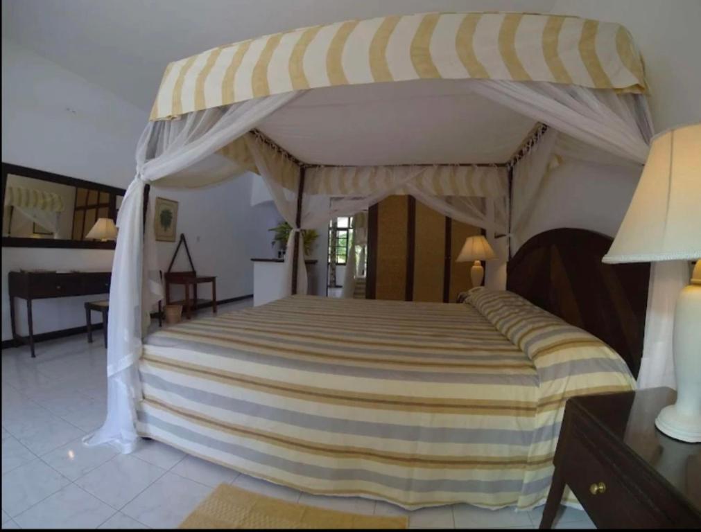 a bedroom with a large bed with a canopy at Woburn Apartments 5C in Malindi