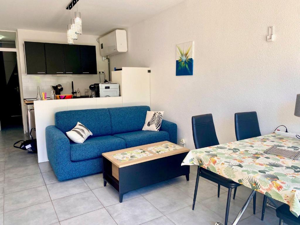un salon avec un canapé bleu et une table dans l'établissement Studio cabine rénové à 250m de l'étang de Thau avec jardinet et parking privé - FR-1-604-3, à Mèze